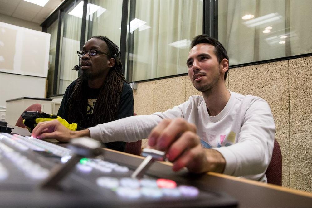 Two film students sitting behind a control panel.